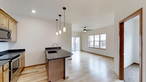 A spacious and modern open-concept kitchen and living room area, featuring sleek pendant lighting and ample natural light.
