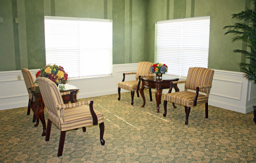 A cozy and elegantly decorated seating area with striped chairs and a table adorned with fresh flowers.