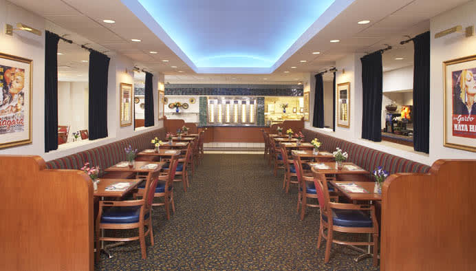 A modern restaurant dining area with neatly arranged tables and chairs, featuring stylish lighting and decor.
