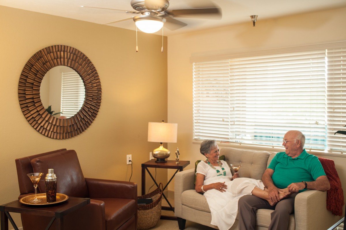 Two people sit on a sofa in a cozy living room, engaged in conversation.