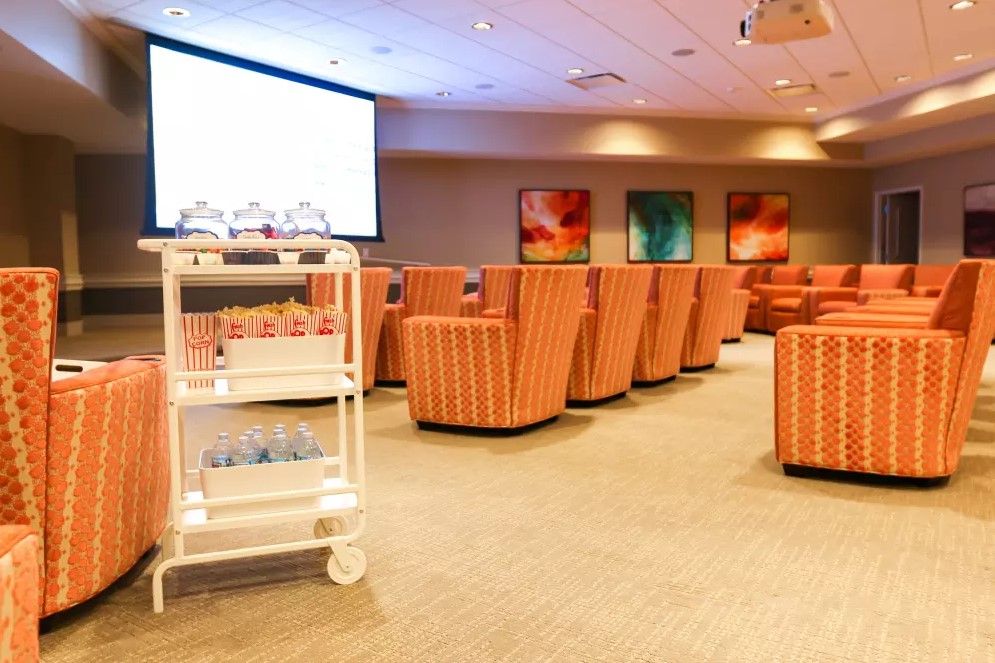 A comfortable lounge with striped chairs and a large screen, featuring a service cart in the foreground.