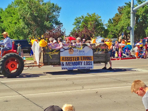 A vibrant parade featuring a banner promoting assisted living and memory care services.