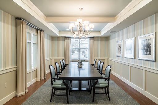 A beautifully designed dining room featuring a long wooden table and elegant chandelier, complemented by stylish chairs and soft natural lighting.
