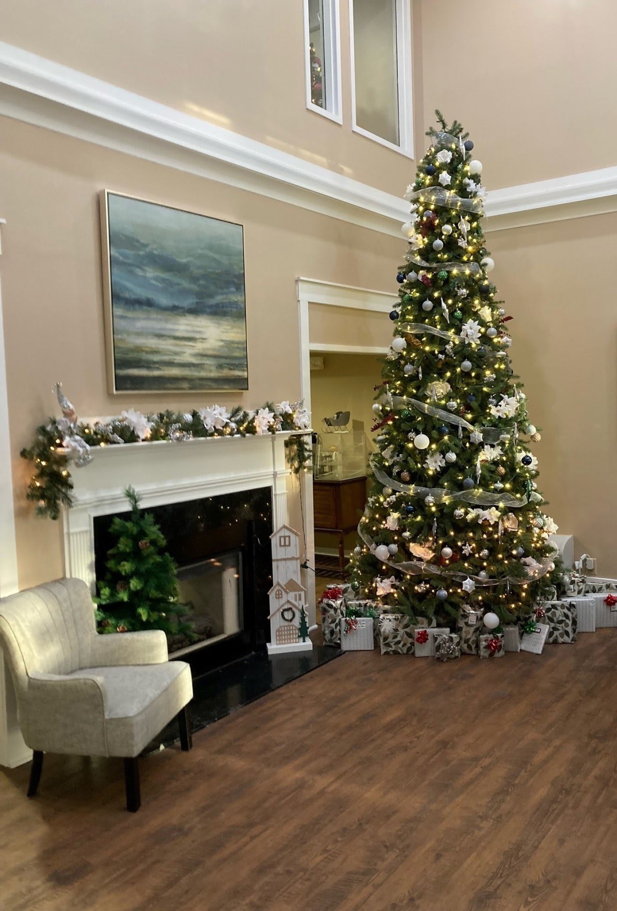 A beautifully decorated Christmas tree stands next to a fireplace adorned with garlands, creating a festive holiday atmosphere.