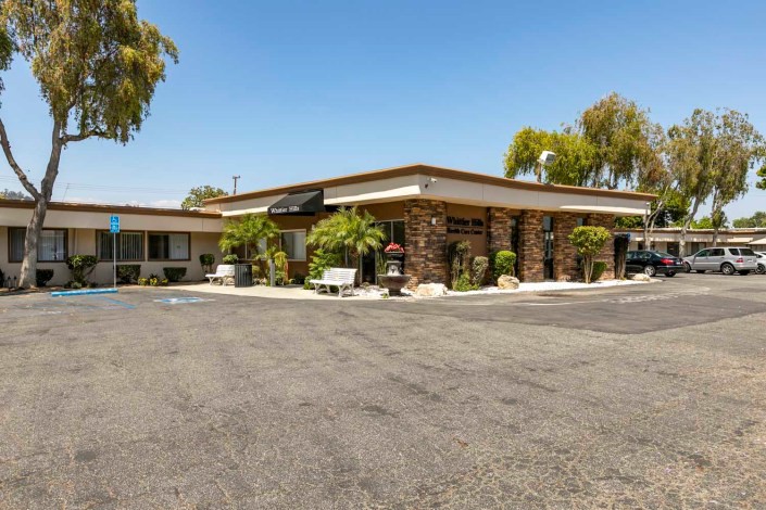 A view of a motel with a parking lot and surrounding trees.