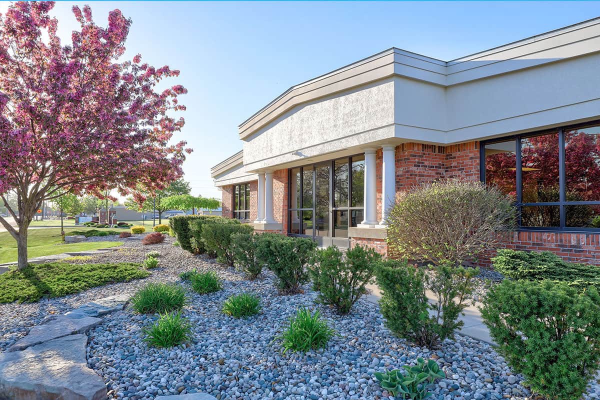 A commercial building with well-maintained landscaping and a clear blue sky.