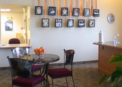 A cozy cafe interior with framed artwork on the wall and a small round table with chairs.