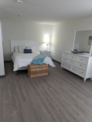 A serene and minimalistic bedroom featuring a cozy bed, a stylish dresser, and ample natural light.