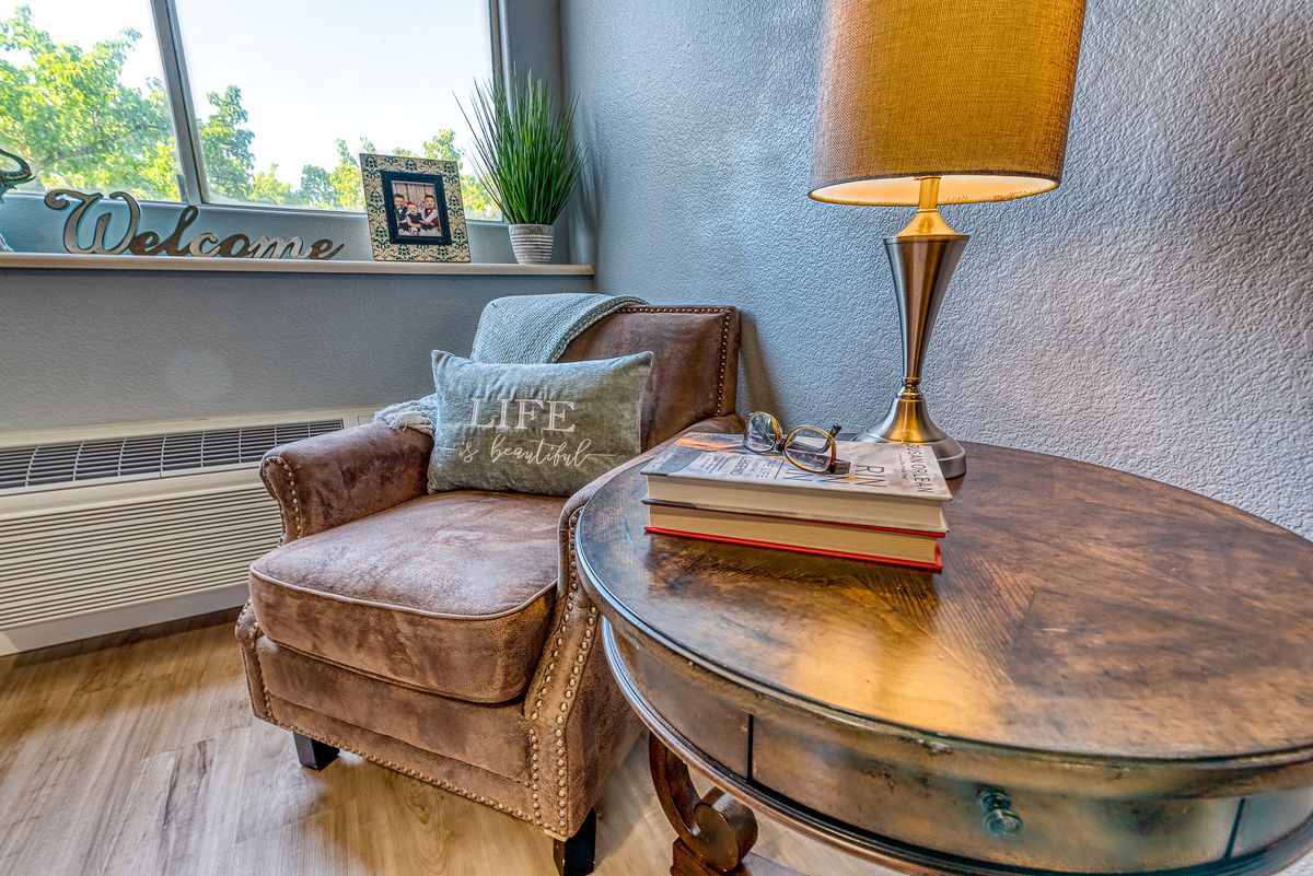 A cozy corner featuring a comfortable armchair, side table with books, and a stylish lamp.
