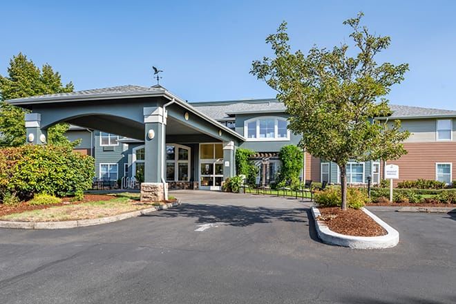 A modern building with a landscaped entrance and driveway.