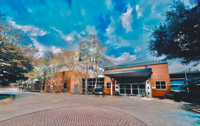 A brick building with a modern entrance under a vivid, partly cloudy sky.