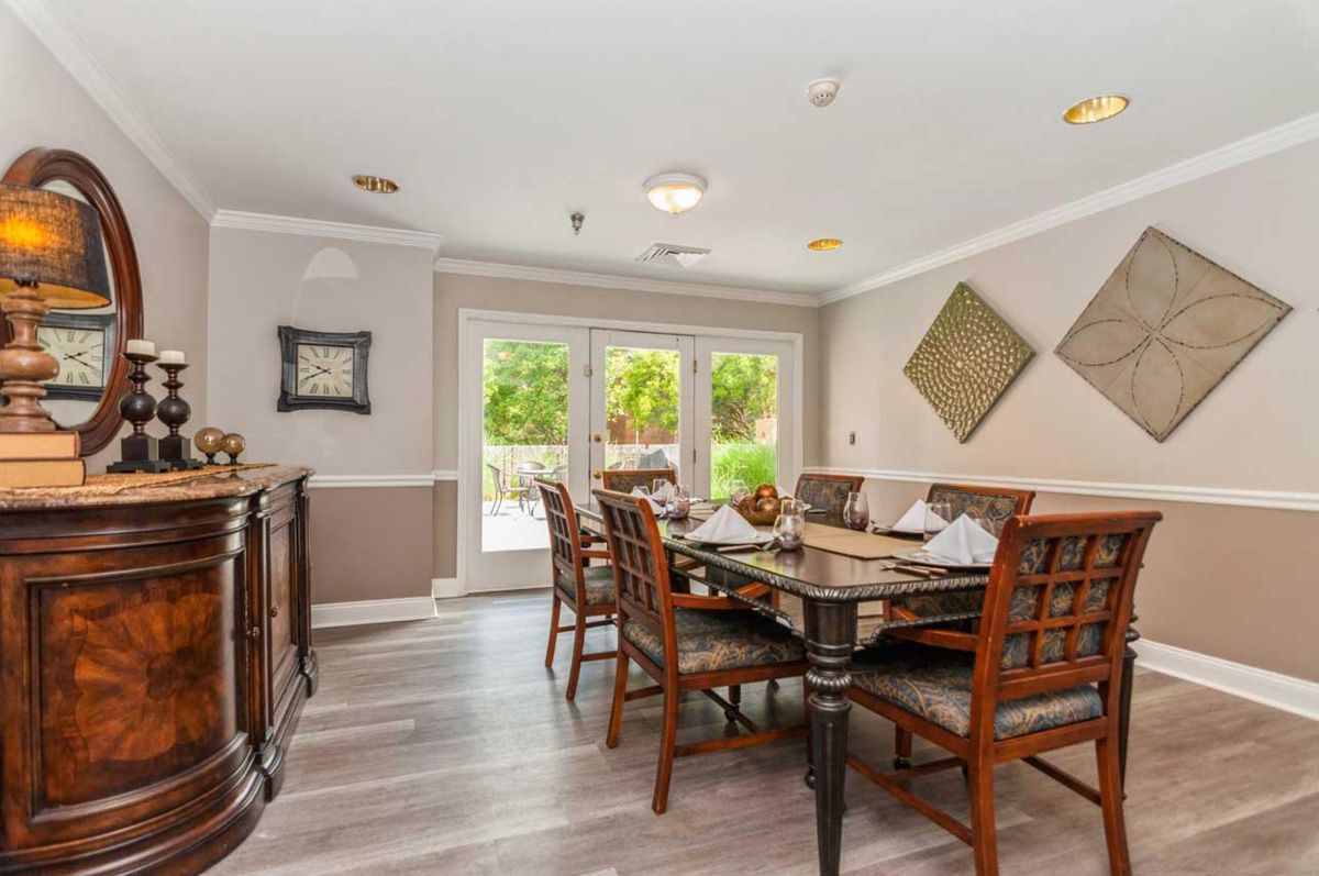 A well-furnished dining room with a wooden table, chairs, and decorative elements by large windows.
