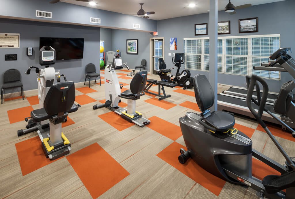 A modern gym with various exercise equipment, including treadmills and stationary bikes.