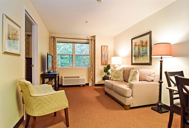 A cozy living room with a sofa, television, and artwork on the walls.