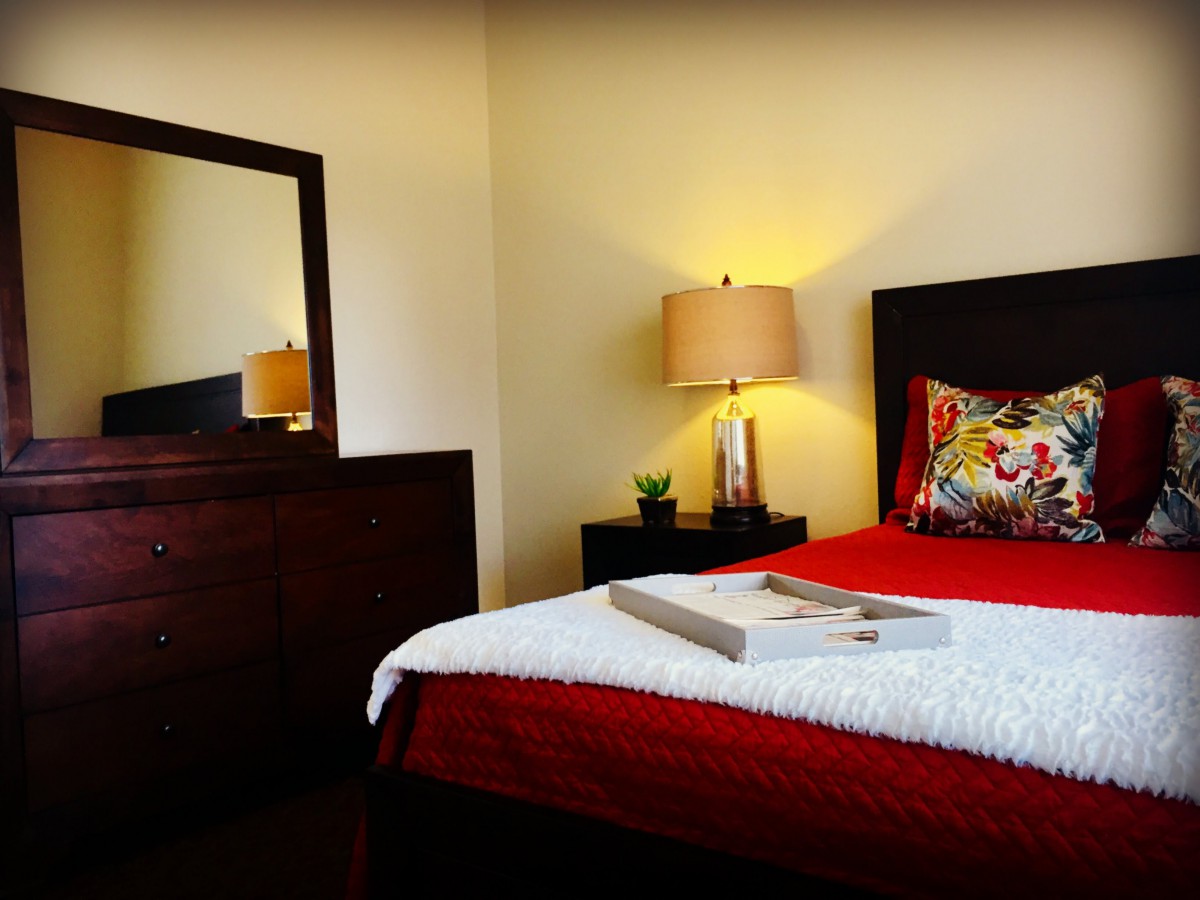 A cozy bedroom with a neatly made bed, featuring warm lighting and stylish decor.
