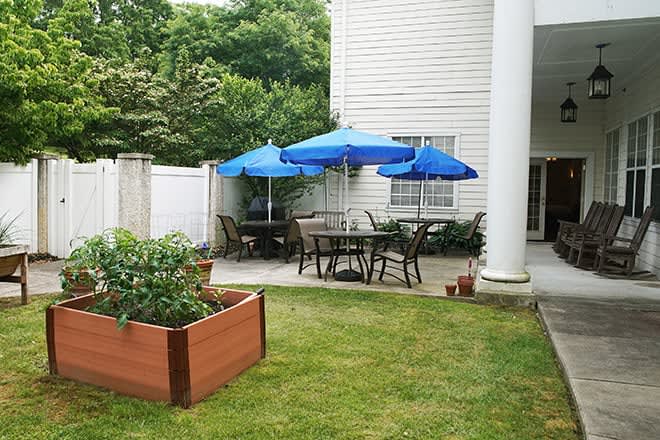 A cozy backyard patio with blue umbrellas and a small garden area.