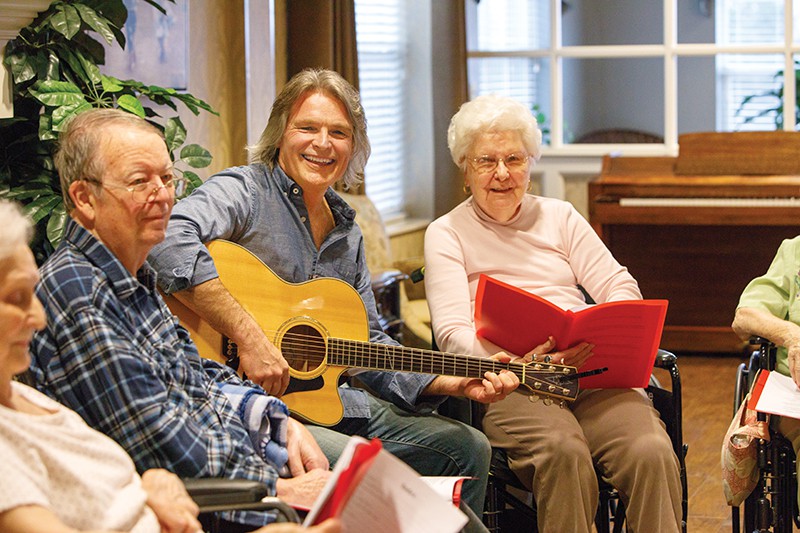 A group of seniors enjoying a music session with a guitarist.