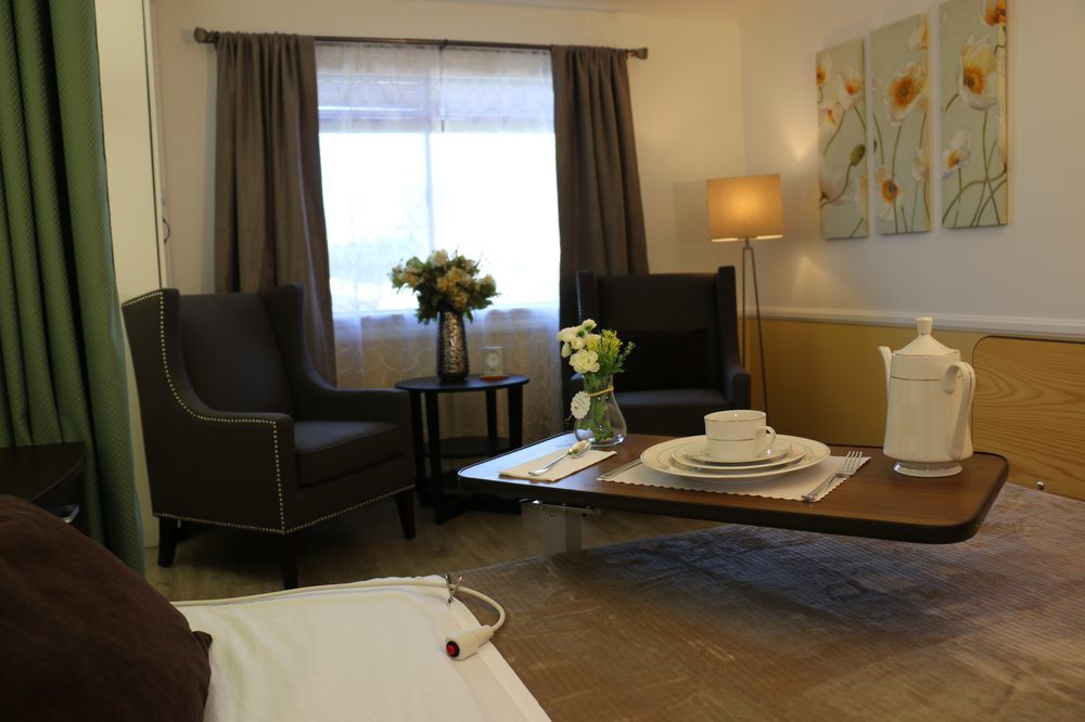 A cozy living room featuring armchairs, a coffee table set with dishes, and floral decorations under soft lighting.