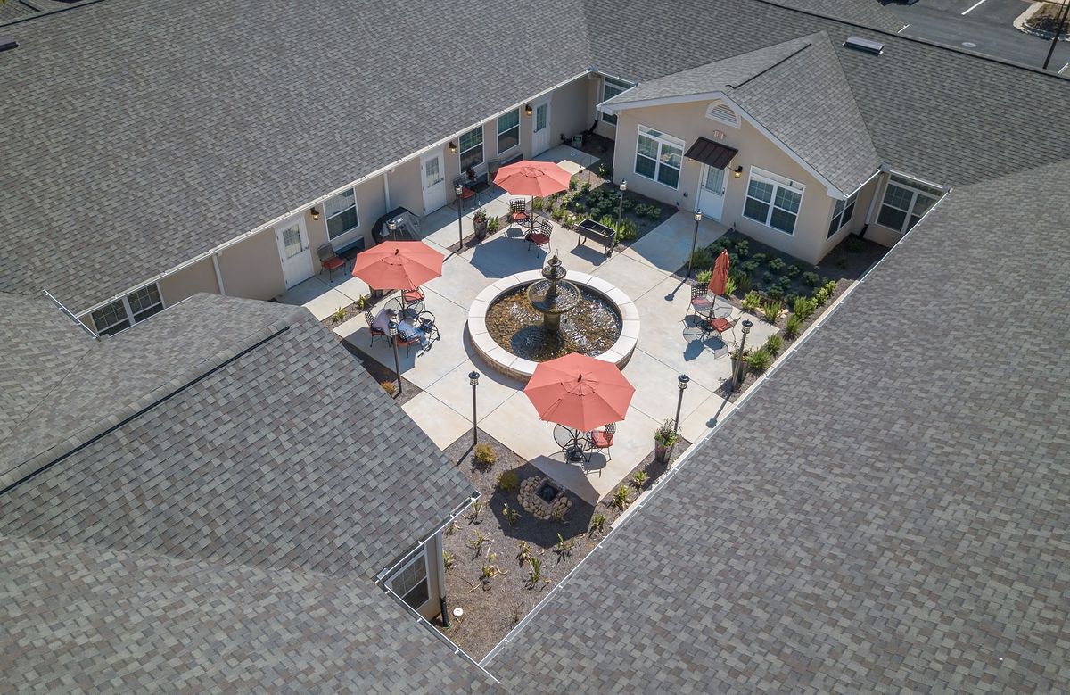 Aerial view of a courtyard with a central fountain surrounded by patio seating and red umbrellas.