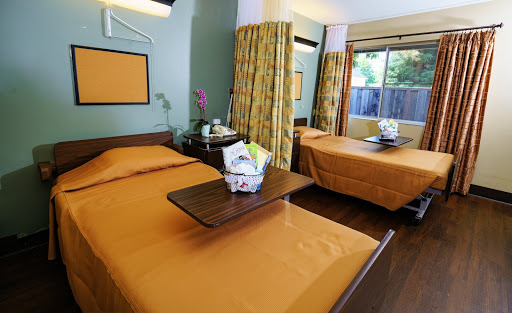 A cozy hotel room featuring two beds with orange bedding and a lovely flower arrangement.