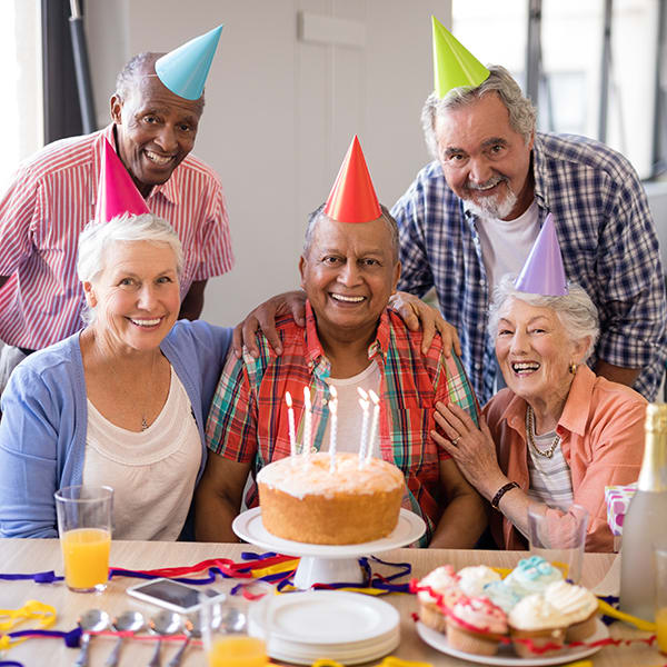 A group of seniors celebrating a birthday with cake and party hats.