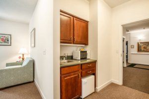 A compact kitchenette with wooden cabinets, a sink, a fridge, and a microwave.