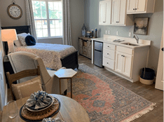 A cozy studio apartment featuring a neatly arranged bedroom and kitchenette area.