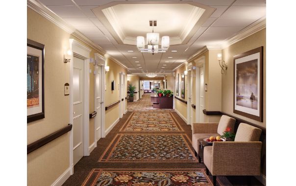 A well-lit hallway with elegant carpeting and seating areas.