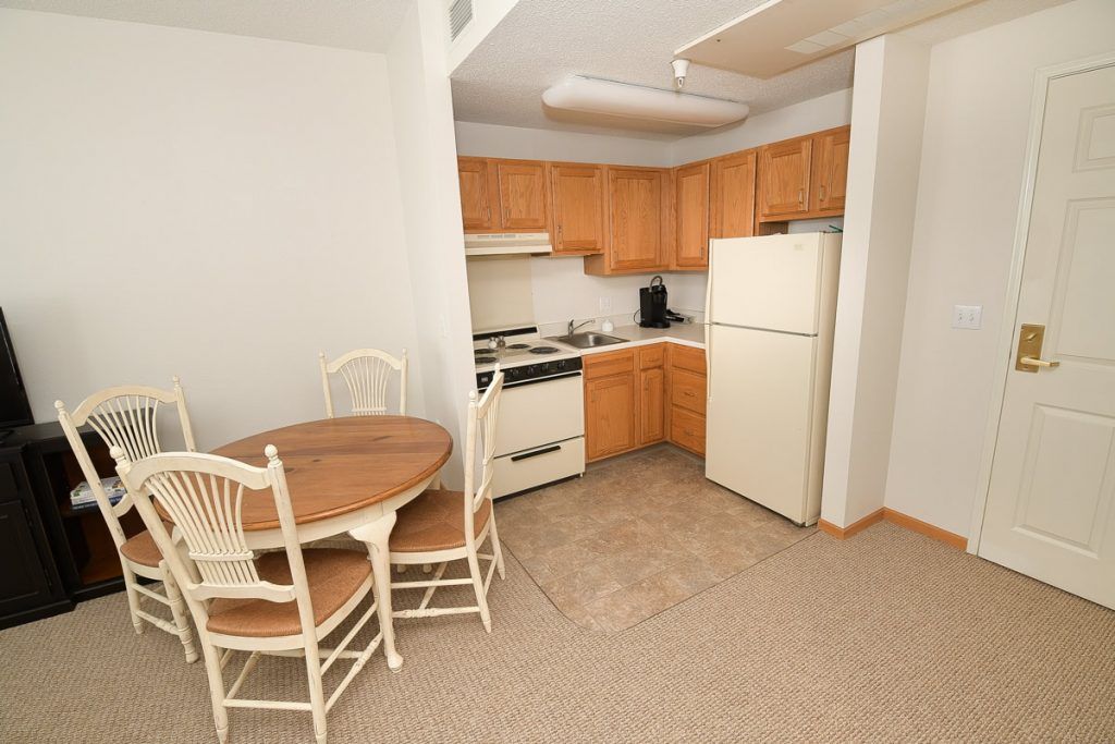 A compact kitchen and dining area with a small round table, chairs, and basic appliances.