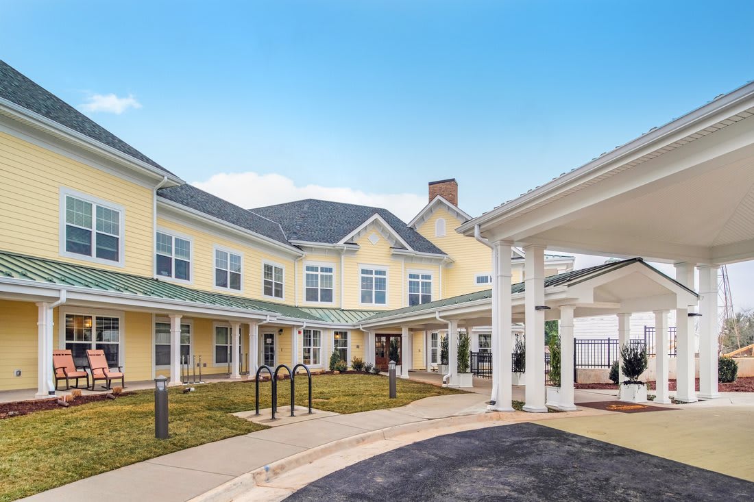 A two-story yellow residential building with a covered entrance and well-maintained grounds.