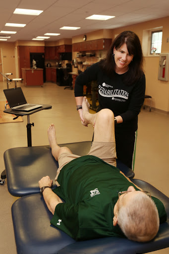 A physical therapist working with a patient to improve leg mobility during a rehabilitation session.