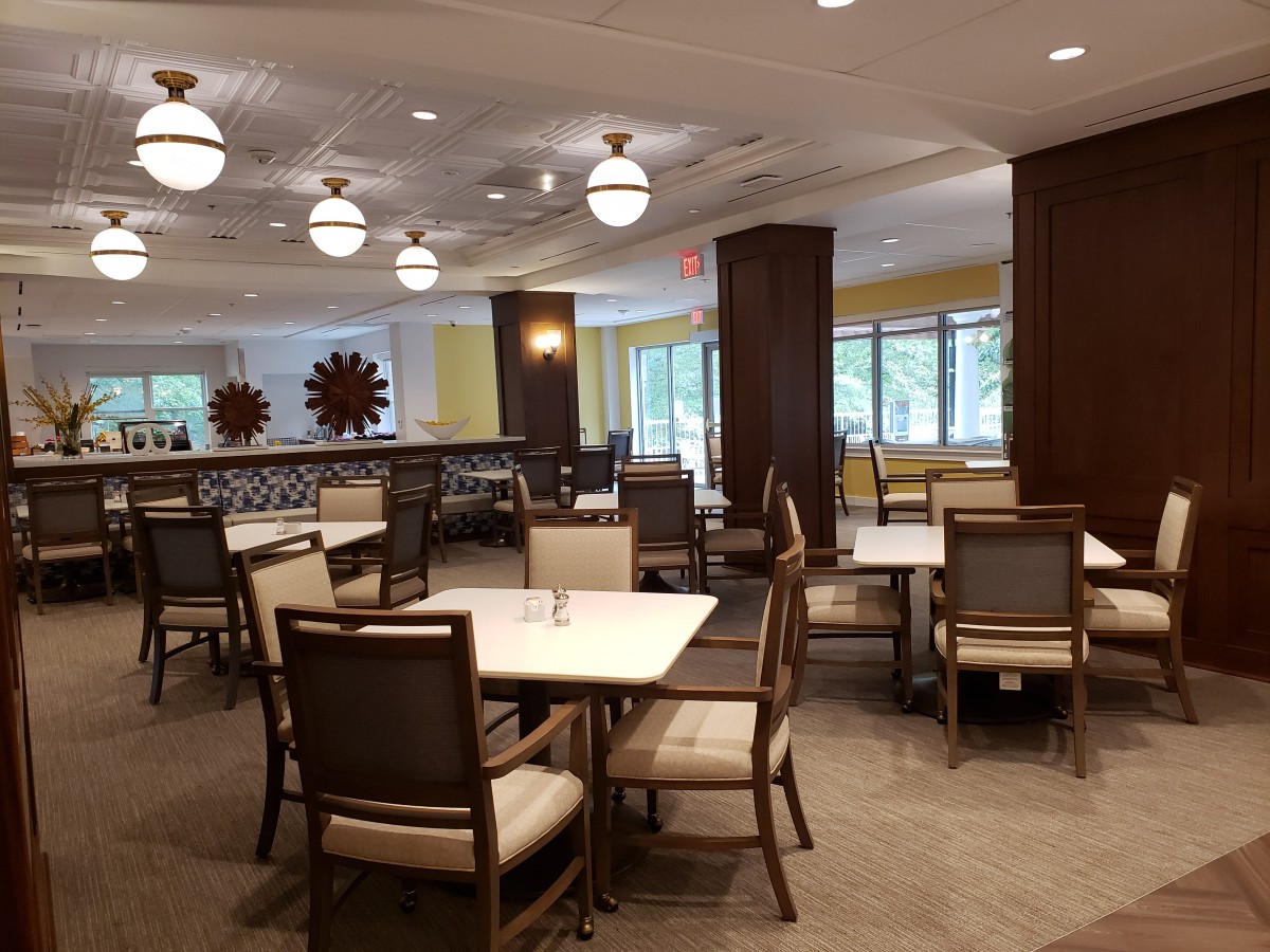 A modern restaurant dining area with neatly arranged tables and chairs under decorative lighting.