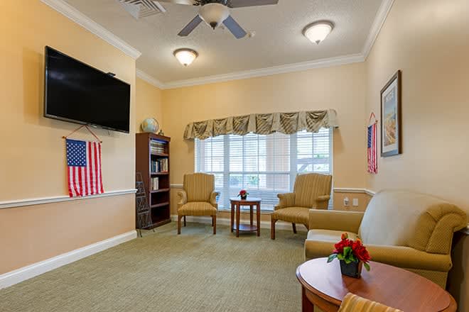 A cozy living room with comfortable chairs, a television, and a ceiling fan.