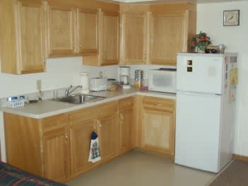 A kitchen with wooden cabinets, a refrigerator, and a microwave.