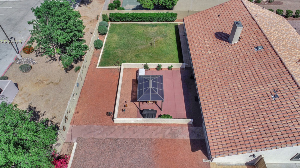Aerial view of a backyard featuring a patio with a gazebo, lawn, and landscaping.