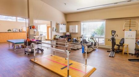 A well-equipped physical therapy and rehabilitation room with exercise equipment and parallel bars.