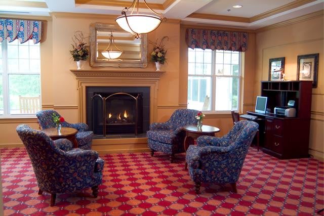 A cozy lobby area featuring armchairs around a fireplace with a decorative carpet.