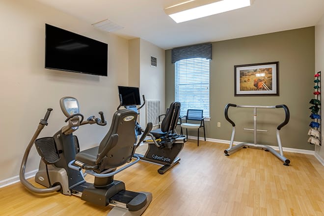 A compact fitness room equipped with stationary bikes and a treadmill.