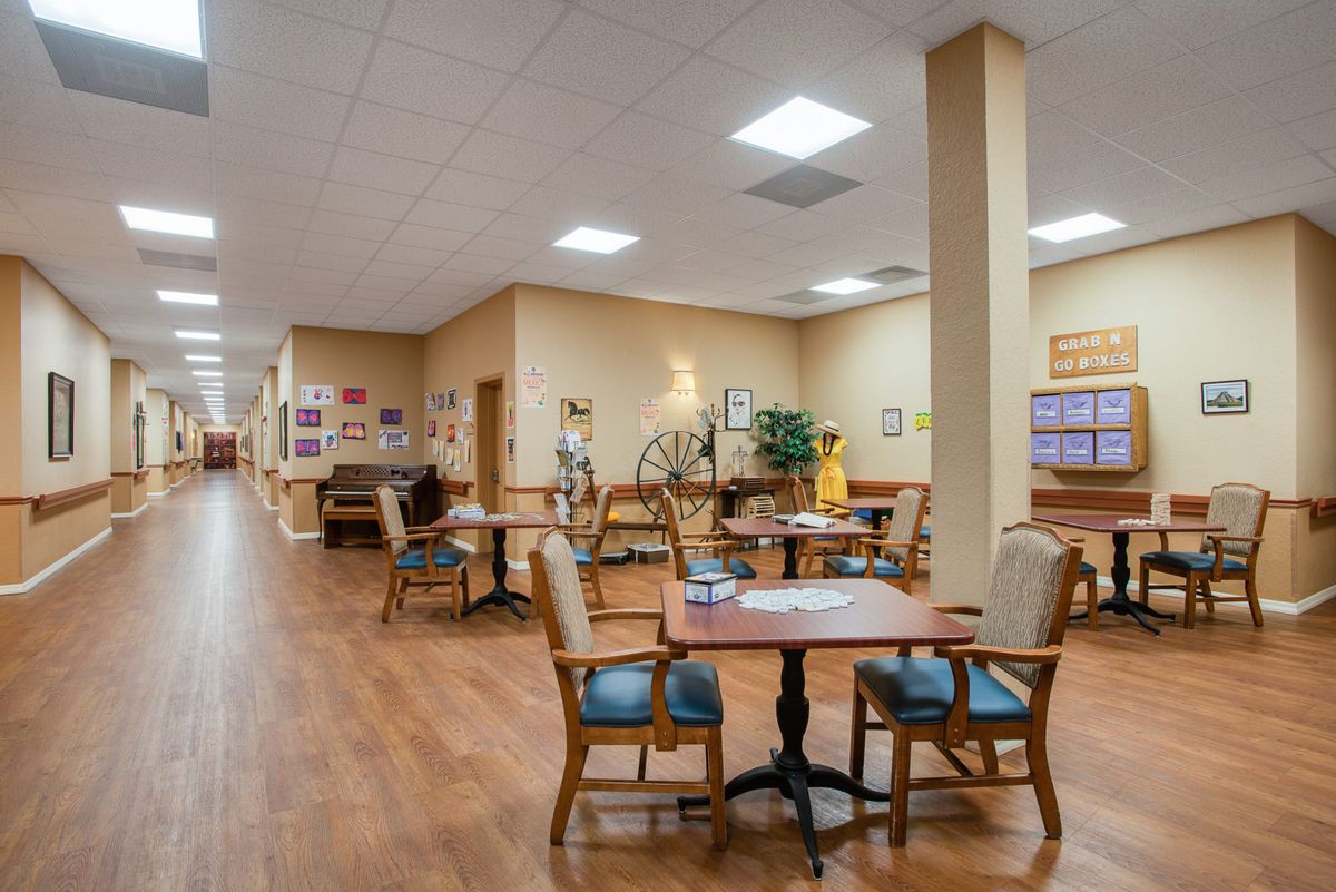 A spacious lobby area featuring tables and chairs, with warm lighting and decorative elements.