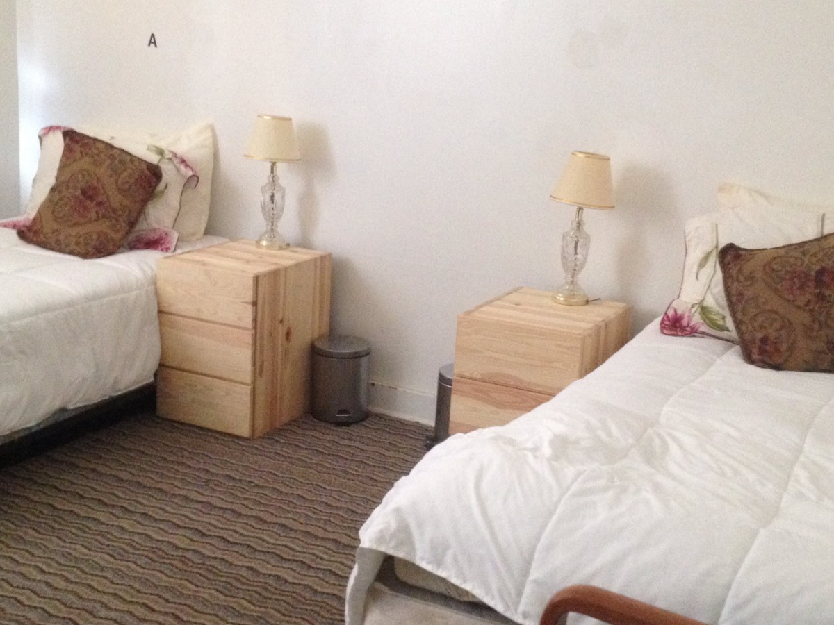 A minimalist bedroom featuring twin beds with wooden nightstands and lamps.