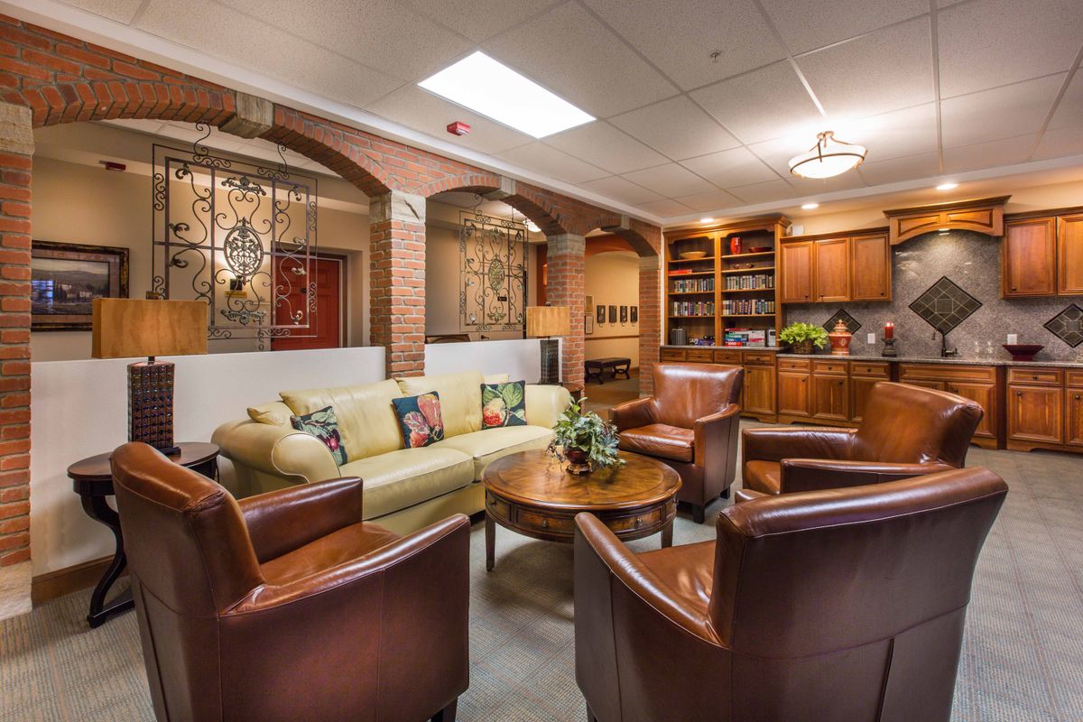 A cozy living room with a sofa, leather chairs, and bookshelves creating a warm atmosphere.