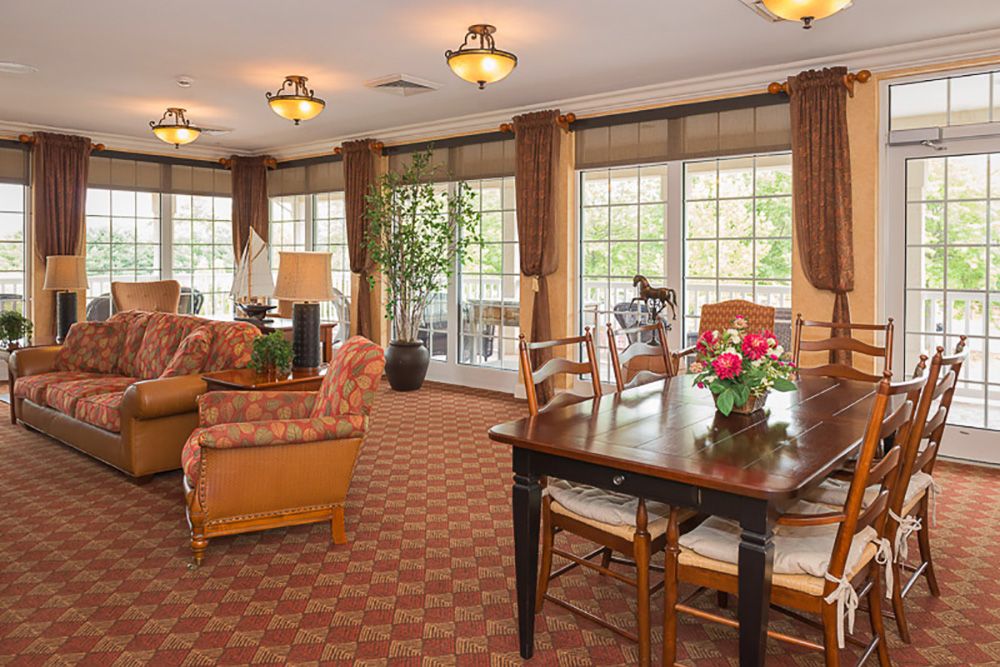 A cozy living room with a dining area, featuring comfortable sofas and a large window view.
