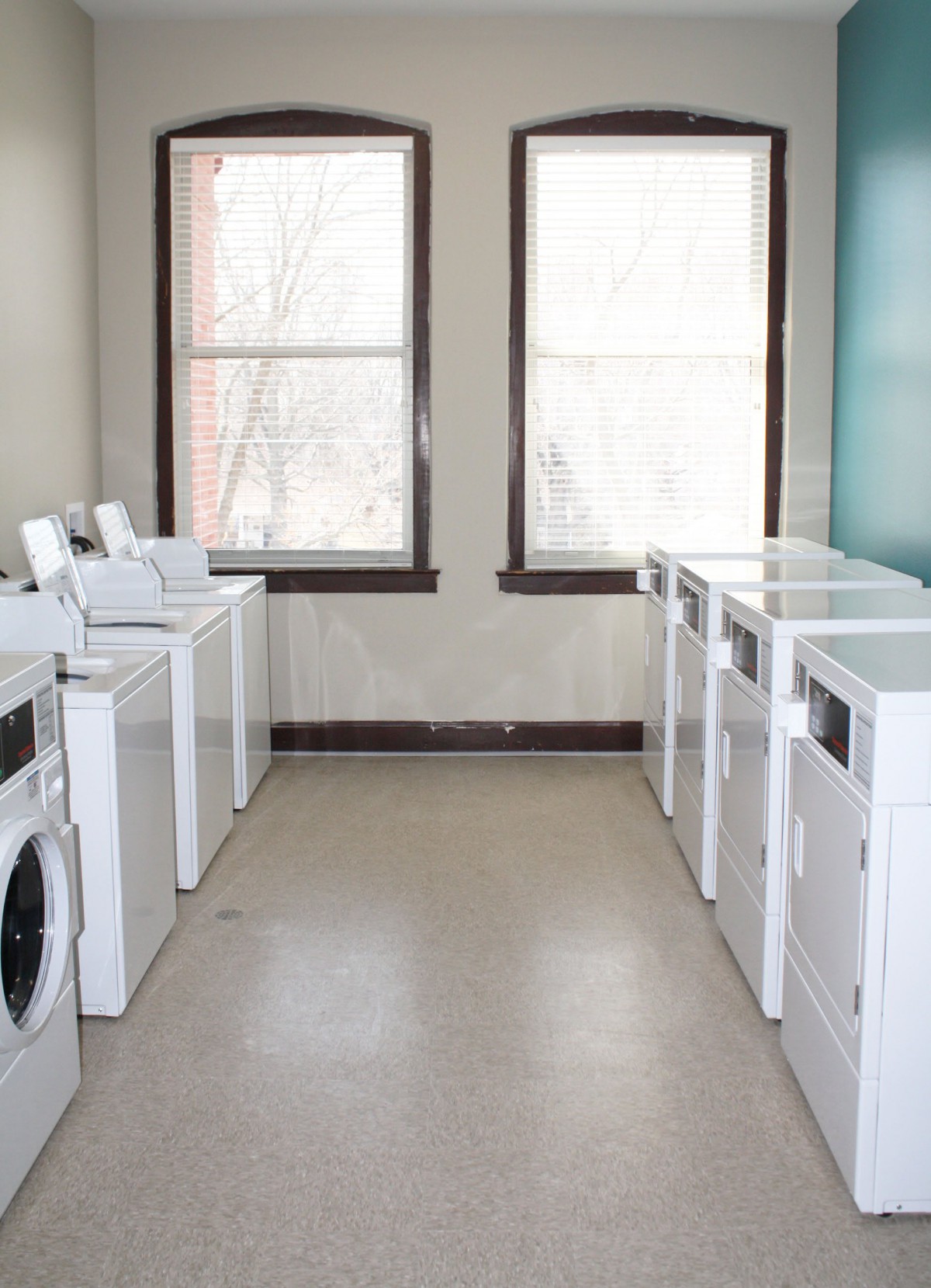 A clean and organized laundry room with multiple washing machines and dryers.