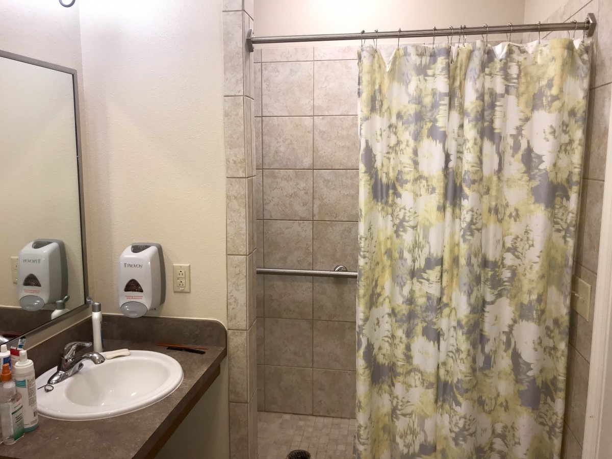 A modern bathroom with a sink, tiled shower, and patterned shower curtain.