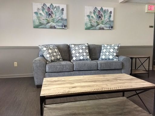 A cozy living room setup featuring a gray sofa adorned with patterned cushions, complemented by a wooden coffee table and decorative wall art.