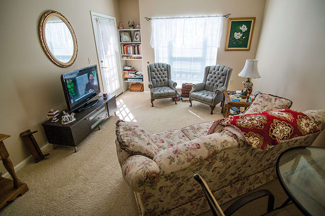 A cozy living room with a floral couch, two patterned chairs, and a television.