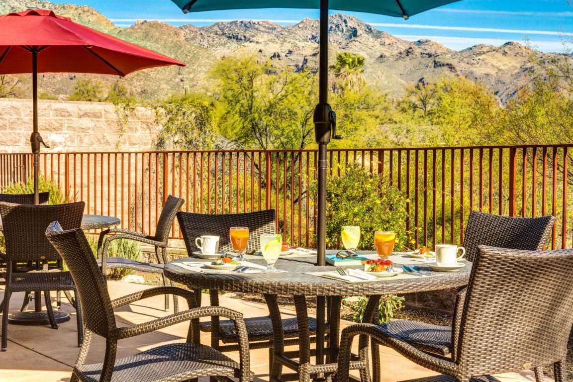 A patio table set for outdoor dining with a desert mountain view.