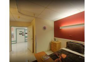 A well-lit hospital room with a comfortable bed and modern furnishings.