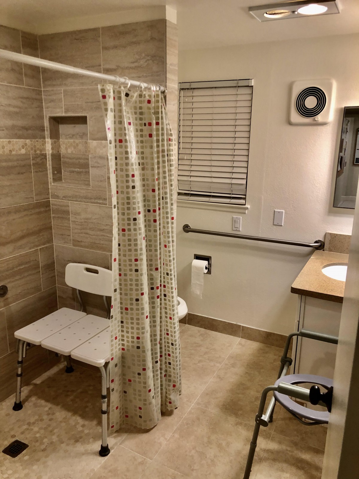 An accessible bathroom with a shower chair and safety bars.