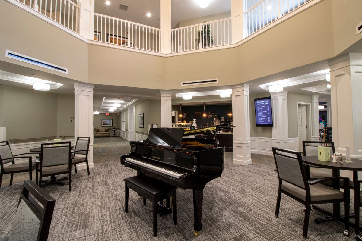 A grand piano in a spacious lobby area with seating and elegant architecture.